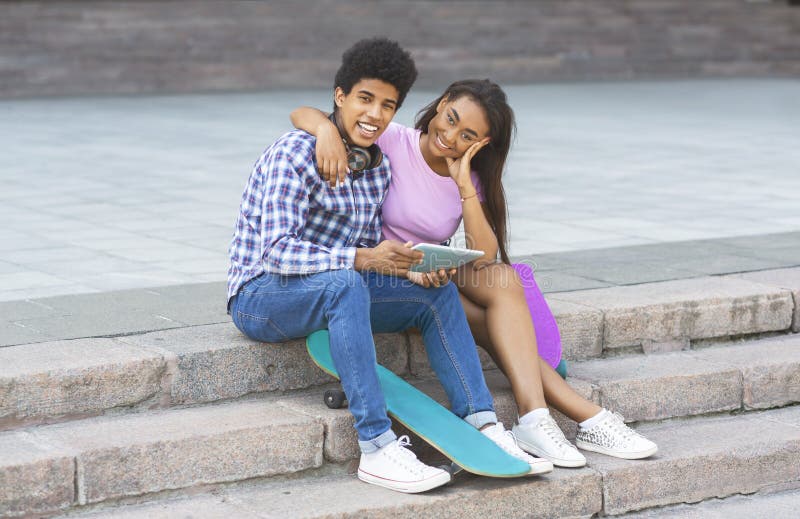 Couple of teenagers sitting on stairs with digital tablet stock photography Couple of teenagers sitting on stairs with digital tablet stock photography