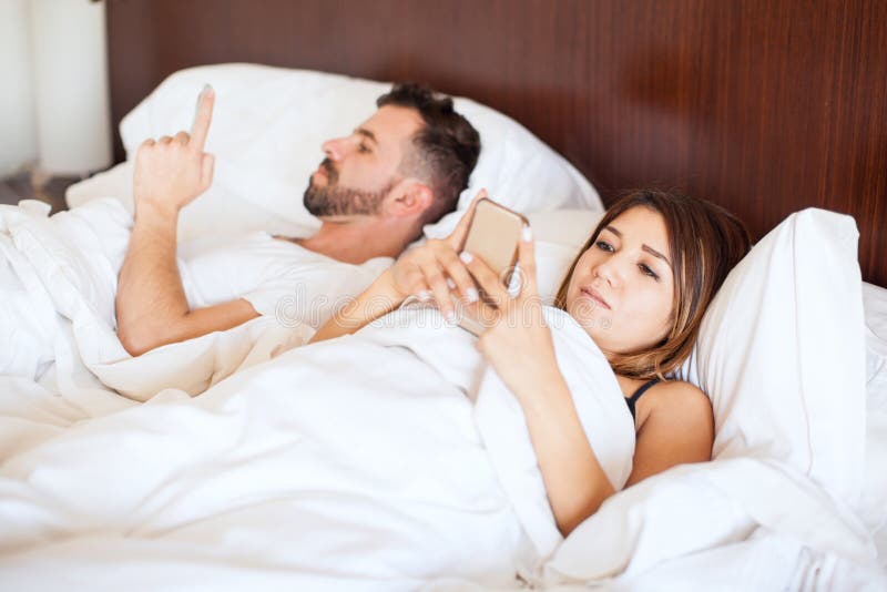 Couple texting on their phones in bed royalty free stock image Couple texting on their phones in bed royalty free stock image
