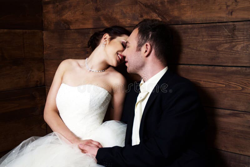 Couple in their wedding clothes in barn with hay