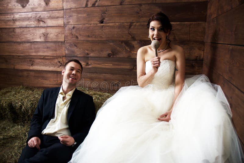 Couple in their wedding clothes in barn with hay