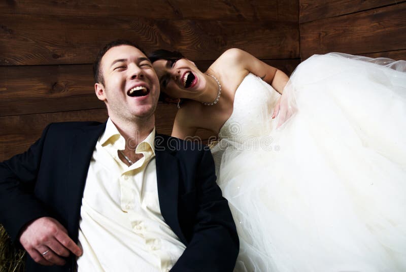 Couple in their wedding clothes in barn laughing