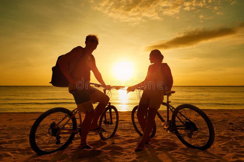 Couple tourists with Bicycles Watching Sunset. Silhouette people