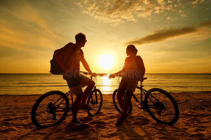 Couple tourists with Bicycles Watching Sunset. Silhouette people