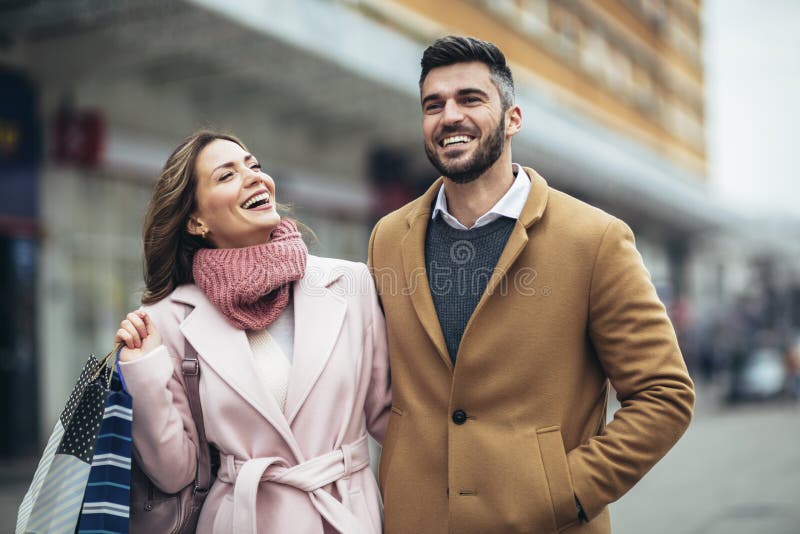 Couple of tourists walking in a city street and shopping together.