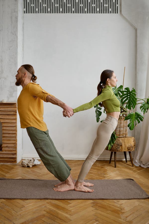 A couple training yoga in pair doing acrobatic plank together stock image