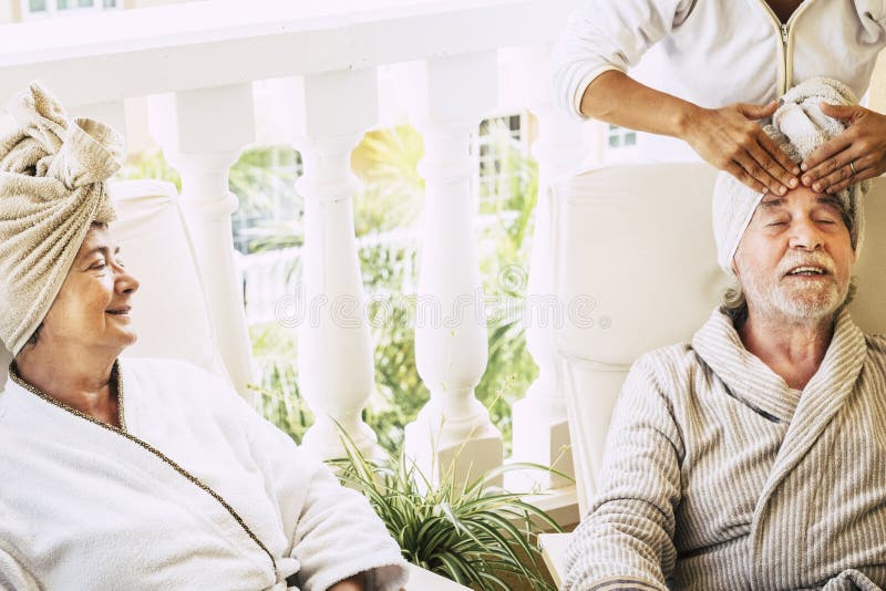 Couple of two pensioner in a resort doing a beauty tratment together with a women assistance doing a massage at the men - mature people at hotel relaxed. Couple of two pensioner in a resort doing a beauty tratment together with a women assistance doing a massage at the men - mature people at hotel relaxed.