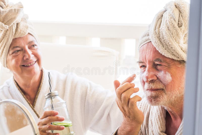 Couple of two seniors or mature people taking a drink or cocktail together at home or in a hotel in a massage treatment.