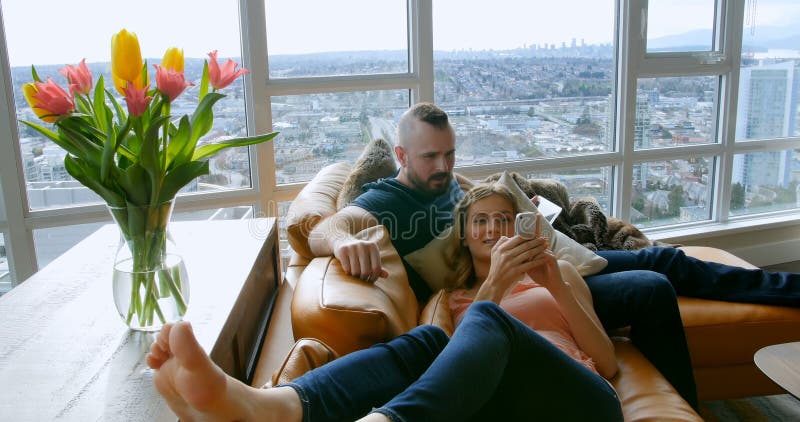 Couple using digital tablet and mobile phone in living room 4k