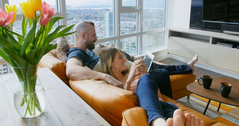 Couple using digital tablet and mobile phone in living room 4k