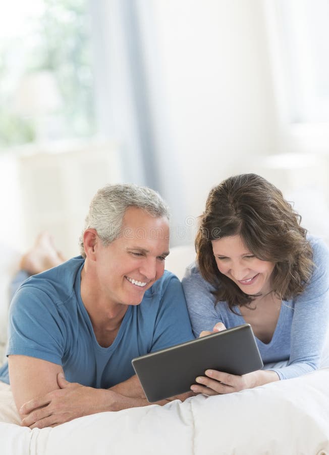 Mature Couple Sharing Digital Tablet On Couch Stockphoto