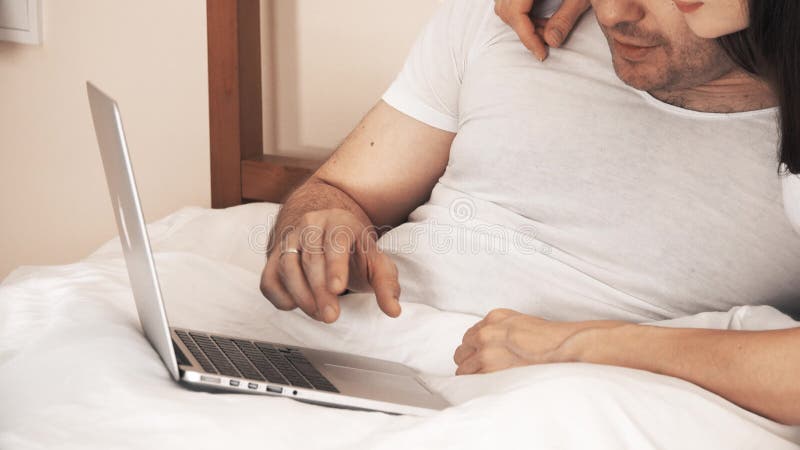 Couple using the laptop in bed