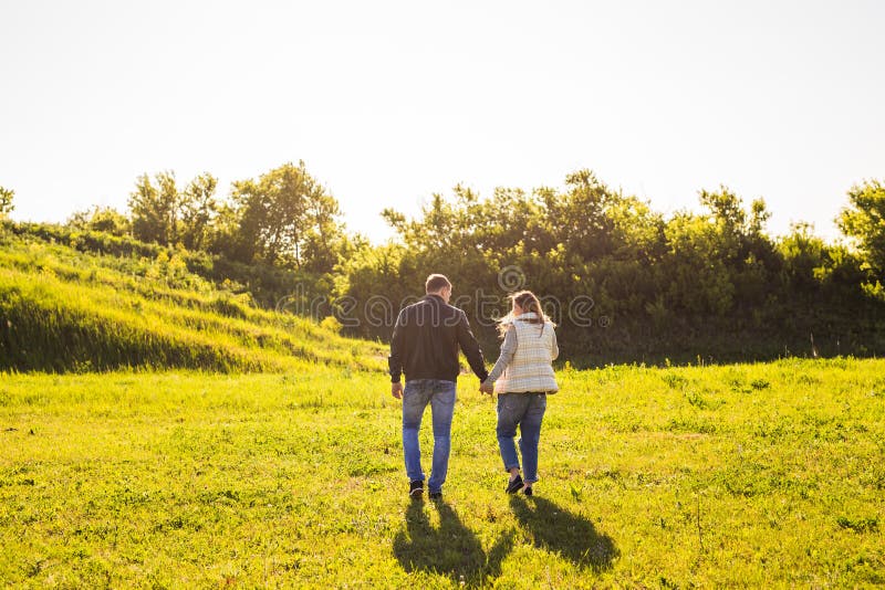 Couple walking in autumn sunset countryside meadow holding hands royalty free stock photo Couple walking in autumn sunset countryside meadow holding hands royalty free stock photo