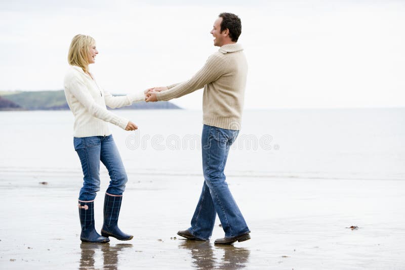 Couple walking on beach holding hands smiling stock photos Couple walking on beach holding hands smiling stock photos