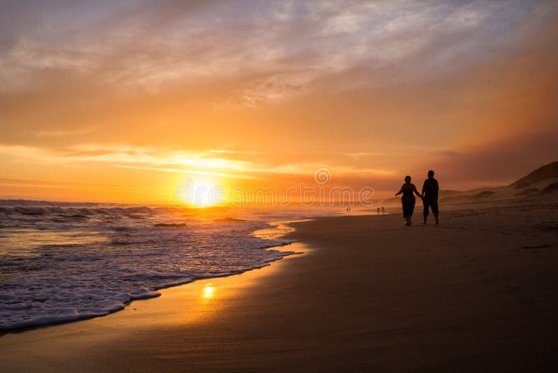 Couple walking on beach at sunset