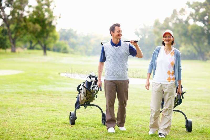 Couple Walking on Golf Course. Full Length of Couple Walking on Golf Course with Golf Bags