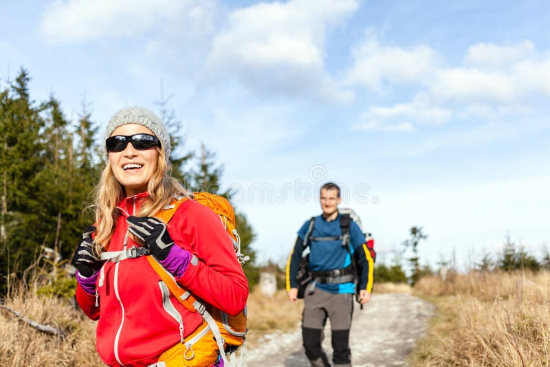 Man and women hikers hiking on mountain trail autumn or winter nature. Young couple backpackers walking in forest landscape. Happy trekkers on travel trip with backpacks, camping outdoors. Man and women hikers hiking on mountain trail autumn or winter nature. Young couple backpackers walking in forest landscape. Happy trekkers on travel trip with backpacks, camping outdoors.