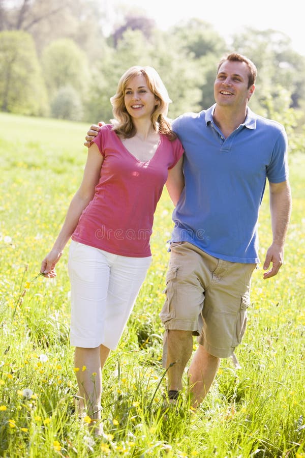 Couple walking outdoors holding flower smiling. Happy embracing couple stock images, royalty-free photos and pictures
