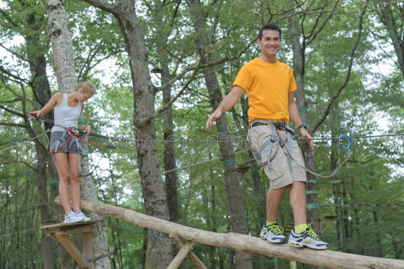 Couple walking on suspended trunk at adventure park