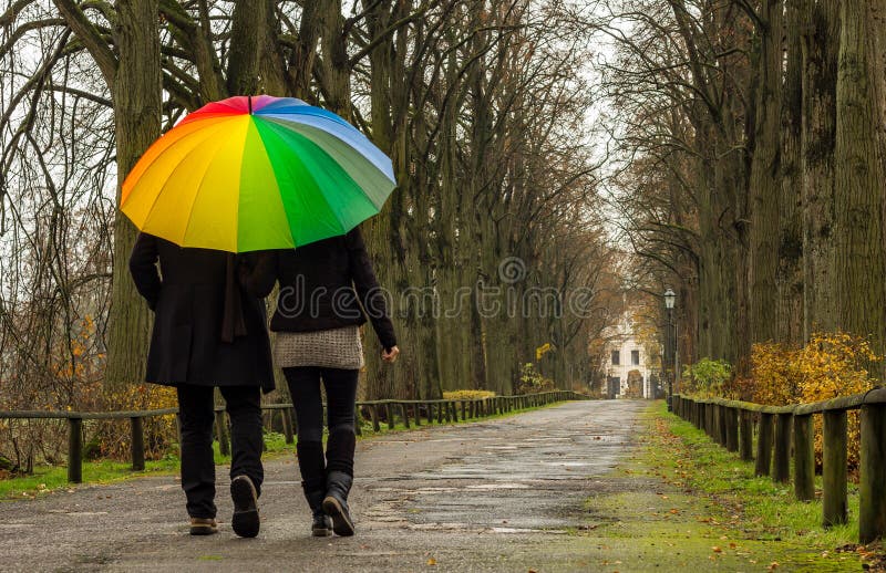 Couple walks under rainbow umbrella