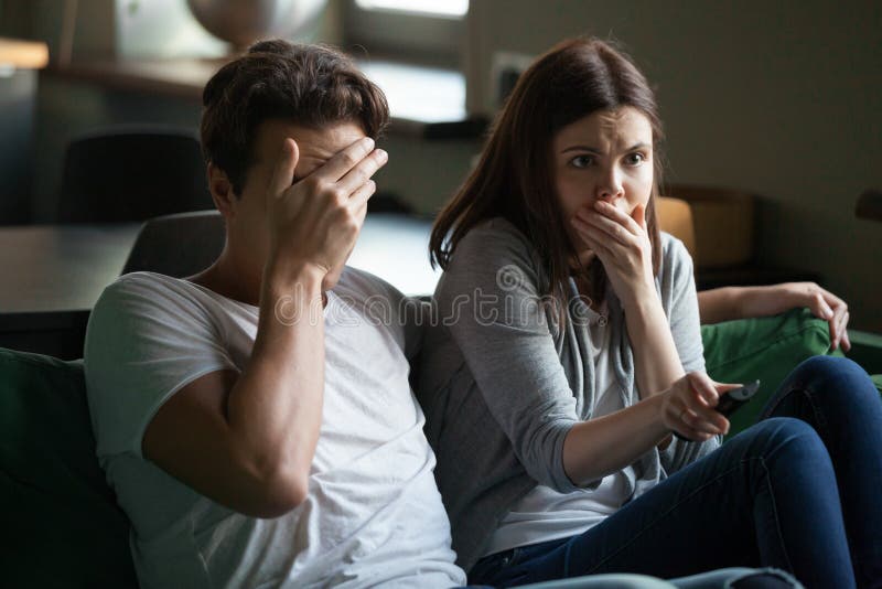 Couple Watching Horror Movie Sitting on Couch at Home Stock Photo