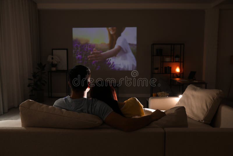 Couple Watching Movie on Sofa at Night. Space for Text Stock Photo
