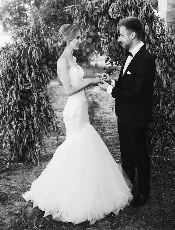 Couple in a wedding dress exchanges rings in the garden with an arch. black and white photo royalty free stock photos Couple in a wedding dress exchanges rings in the garden with an arch. black and white photo royalty free stock photos