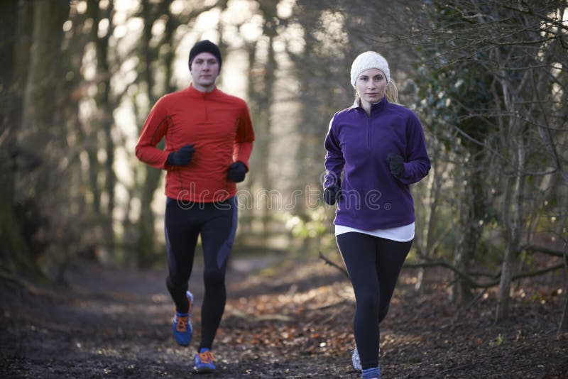 Couple On Winter Run Through Woodland