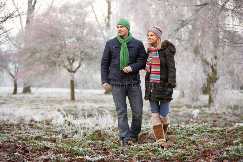 Couple On Winter Walk Through Frosty Landscape