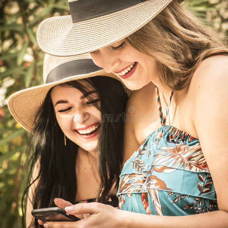 Couple Of Women Young Friends Have Fun Together Using Cellular Phone Connection In Outdoor