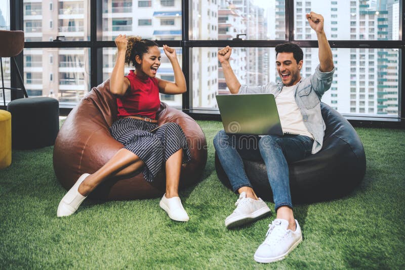 Couple of young designers working at modern office, two coworkers discussing fun project over a laptop, little team of royalty free stock images Couple of young designers working at modern office, two coworkers discussing fun project over a laptop, little team of royalty free stock images