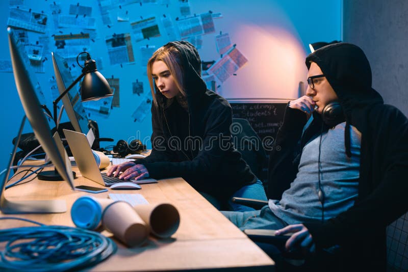 Couple of young hackers using laptop at workplace royalty free stock photos