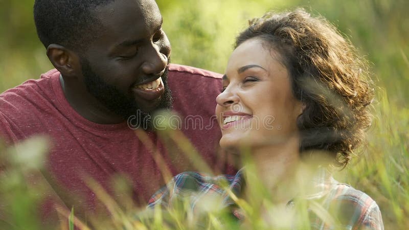 Couples affectueux détendant dehors sur le pique-nique en parc de ville, ayant l'amusement ensemble