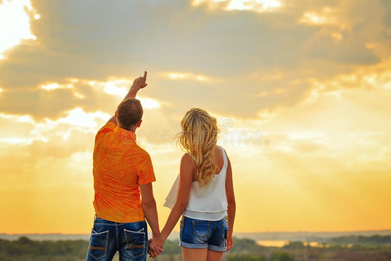 Couples affectueux regardant le ciel le coucher du soleil image stock Couples affectueux regardant le ciel le coucher du soleil image stock