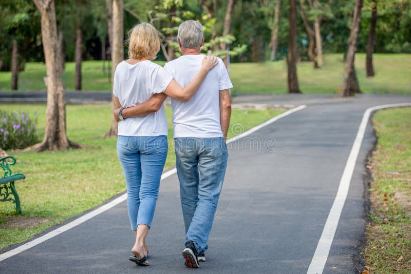 Couples affectueux supérieurs heureux détendant au parc embrassant et marchant ensemble dans le temps de matin personnes âgées ét photo stock