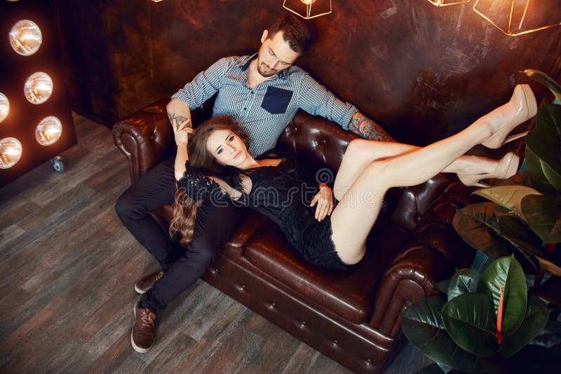Couples aimants étreignant sur le divan contre les lumières lumineuses des lampes La passion et la tendresse, l'homme et la femme photographie stock Couples aimants étreignant sur le divan contre les lumières lumineuses des lampes La passion et la tendresse, l'homme et la femme photographie stock
