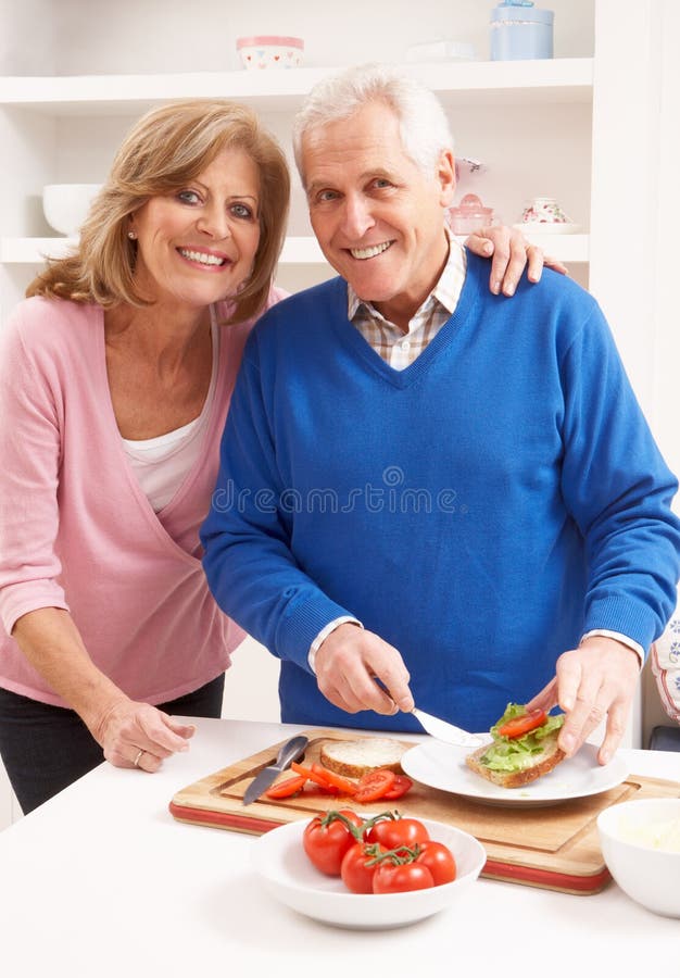Couples aînés effectuant le sandwich dans la cuisine image libre de droits Couples aînés effectuant le sandwich dans la cuisine image libre de droits