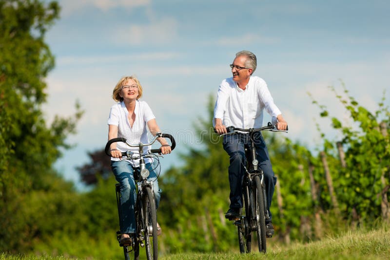 Couples aînés heureux faisant un cycle à l'extérieur en été photos libres de droits