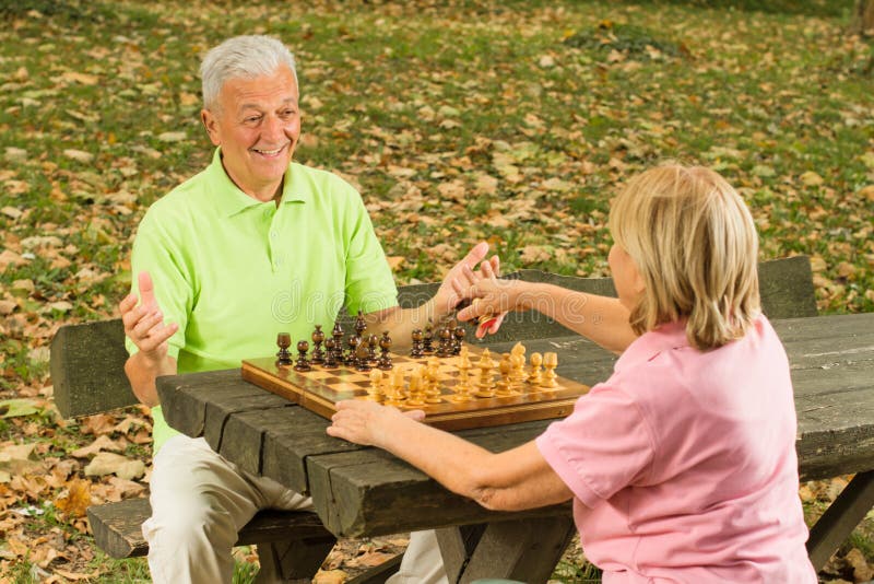 Couples aînés heureux jouant aux échecs image stock Couples aînés heureux jouant aux échecs image stock