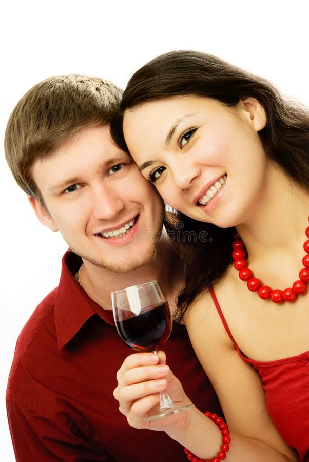 Happy young romantic couple dressed in red embracing and drinking vine. Happy young romantic couple dressed in red embracing and drinking vine