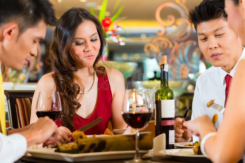 Couples chinois grillant avec du vin dans le restaurant photo libre de droits Couples chinois grillant avec du vin dans le restaurant photo libre de droits