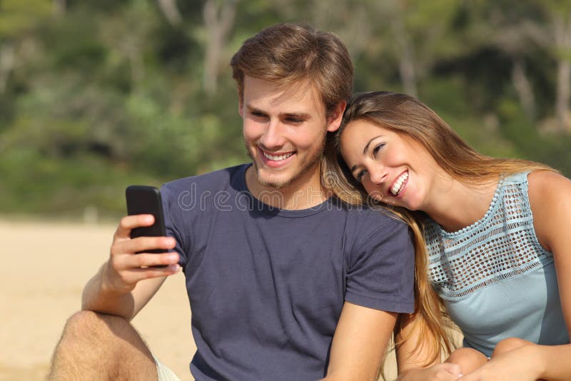 Happy teenager couple sharing social media on the smart phone outdoors. Happy teenager couple sharing social media on the smart phone outdoors
