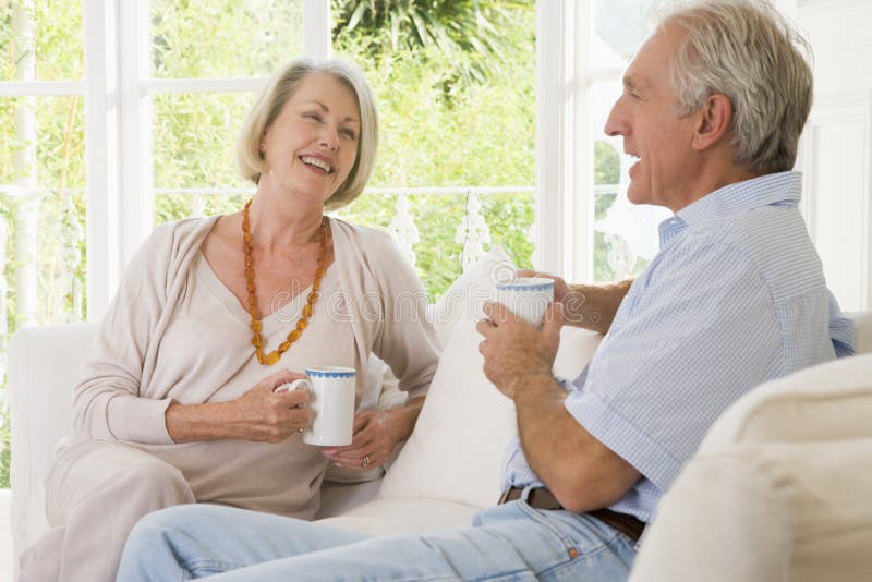 Couples dans la salle de séjour avec le sourire de café image libre de droits Couples dans la salle de séjour avec le sourire de café image libre de droits