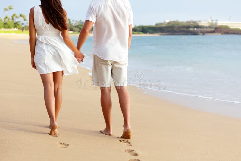 Couples de lune de miel tenant des mains marchant sur la plage
