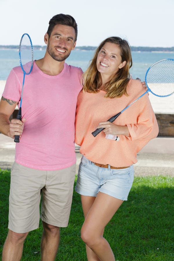 Couples de portrait tenant des raquettes de badminton par le bord de la mer photographie stock libre de droits Couples de portrait tenant des raquettes de badminton par le bord de la mer photographie stock libre de droits