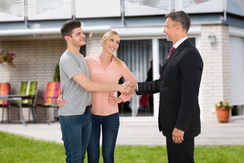Couples de Shaking Hands With d'agent immobilier images stock Couples de Shaking Hands With d'agent immobilier images stock