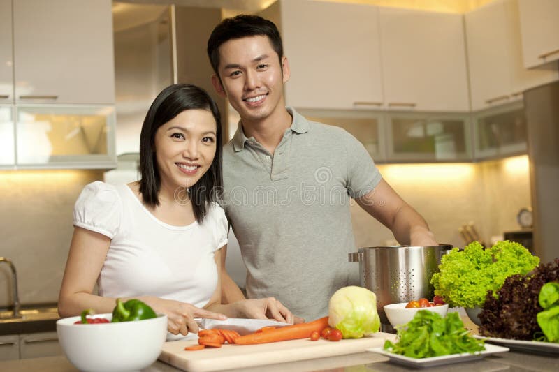 Couples de sourire asiatiques dans la cuisine photos stock Couples de sourire asiatiques dans la cuisine photos stock