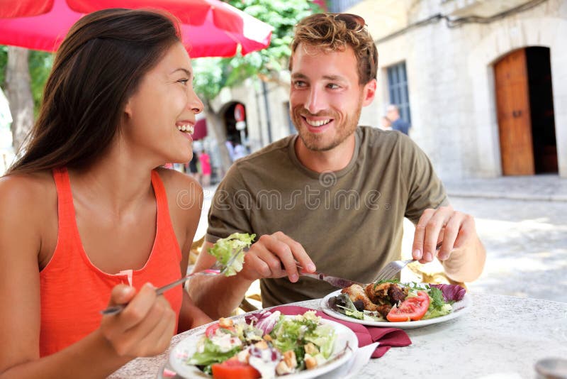 Couples de touristes de restaurant mangeant au café extérieur