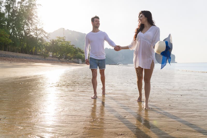 Couples des vacances d'été de plage, beaux jeunes heureux dans l'amour marchant, sourire de femme d'homme tenant des mains photos libres de droits Couples des vacances d'été de plage, beaux jeunes heureux dans l'amour marchant, sourire de femme d'homme tenant des mains photos libres de droits