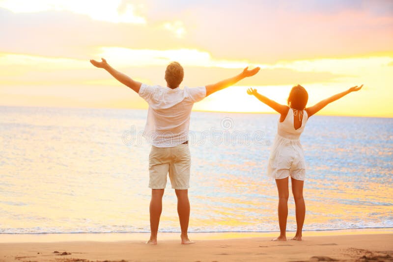 Couples encourageants heureux appréciant le coucher du soleil à la plage
