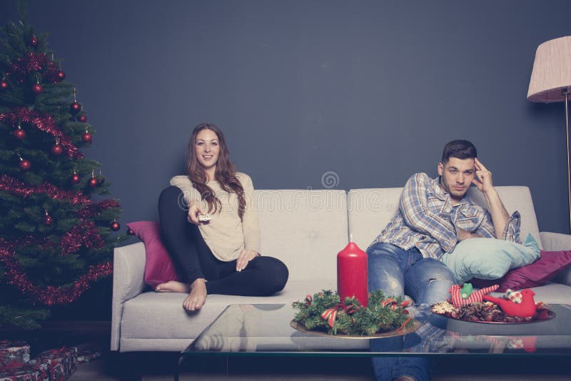 Couples ennuyés à la maison dans l'humeur de Noël photos stock Couples ennuyés à la maison dans l'humeur de Noël photos stock